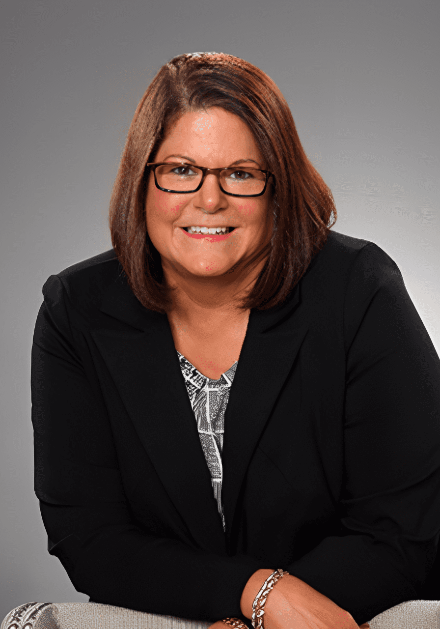 A woman in glasses and black jacket sitting on chair.